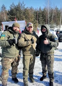 Garkavenko (middle) poses for a photo with camouflage-clad men with Russian military patches on their sleeves.