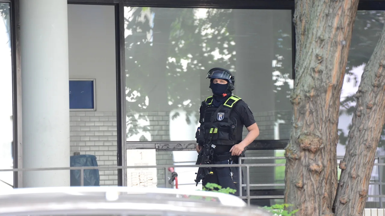 Вооруженный сотрудник охраняет вход в многоквартирный дом на улице Биссингцейле, где в последнее время находился нападавший