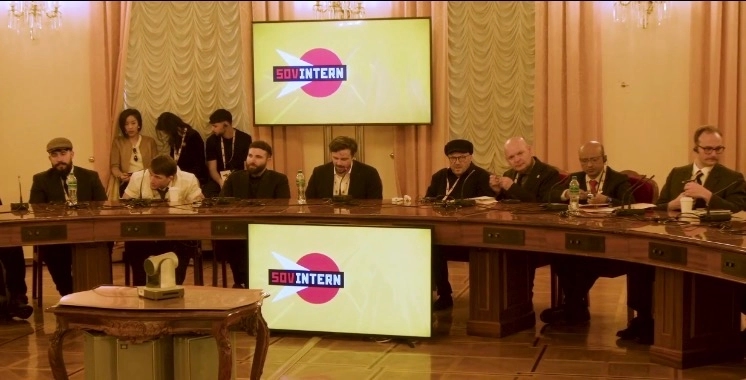 A Sovintern meeting. Among those present are Carlos L. Garrido of the Midwestern Marx Institute, Edward Liger Smith of the American Communist Party and Midwestern Marx Institute, Adam Tahir of the American Communist Party, Jackson Hinkle of the American Communist Party, George Galloway of the Workers Party of Britain, Serbian politician Bajan Vulin, and Kyle Pettis of the American Communist Party and Midwestern Marx Institute