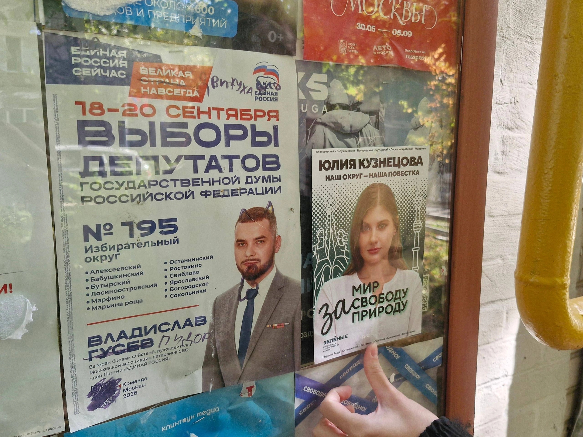 A defaced campaign poster of a candidate from the ruling United Russia party side-by-side with a poster of Yulia Kuznetsova