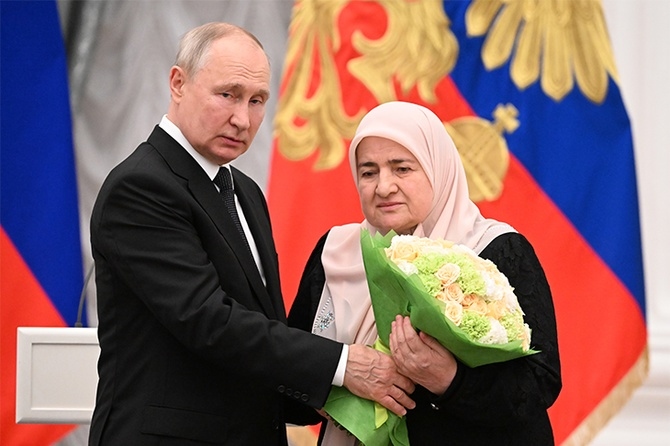 Vladimir Putin gifts flowers to Chechen leader Ramzan Kadyrov's mother, Aimani Kadyrova, during a state reception. Photo: Radio Komsomolskaya Pravda