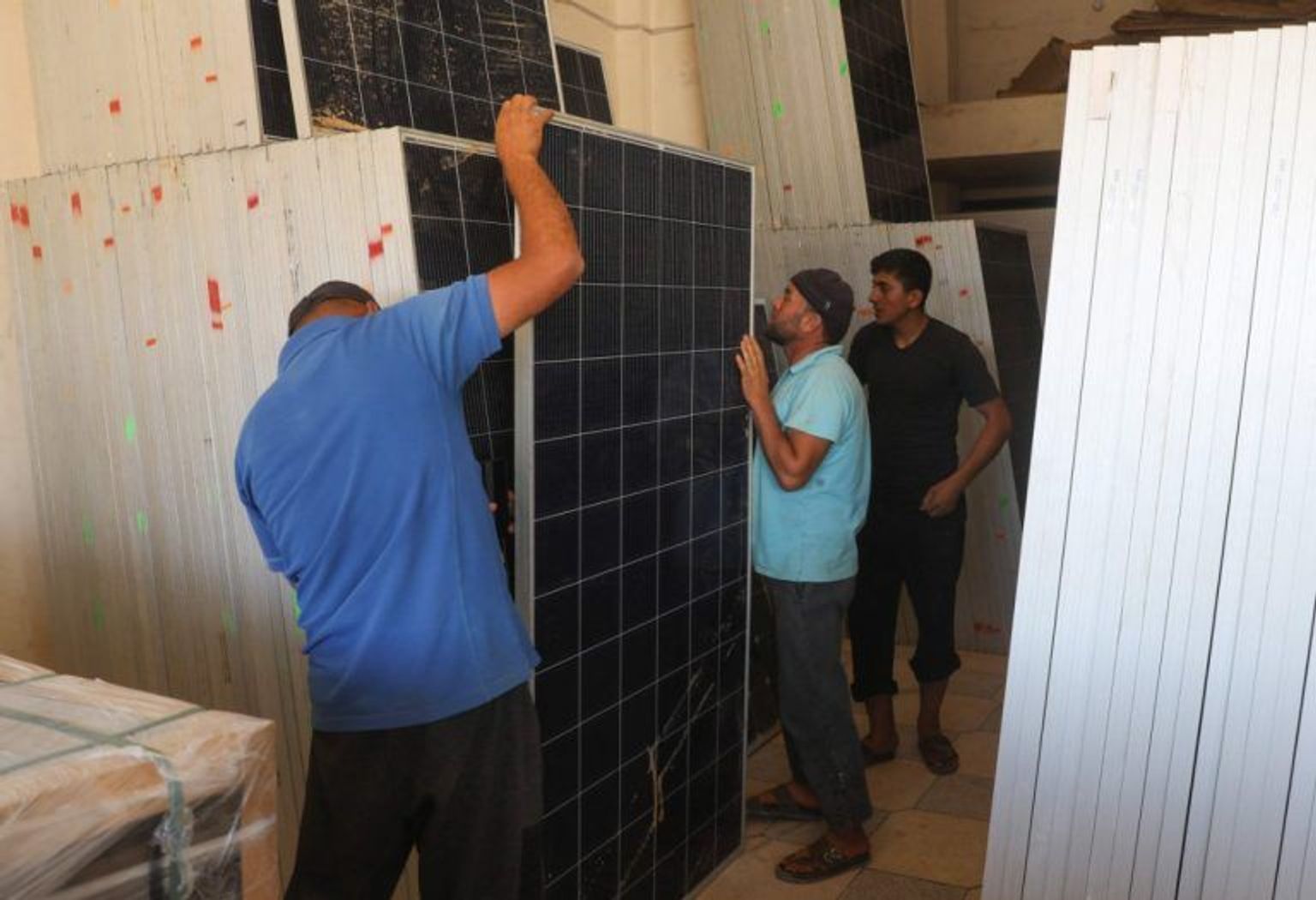 Workers install solar panels on the roof of a shop in Idlib, June 10, 2021.