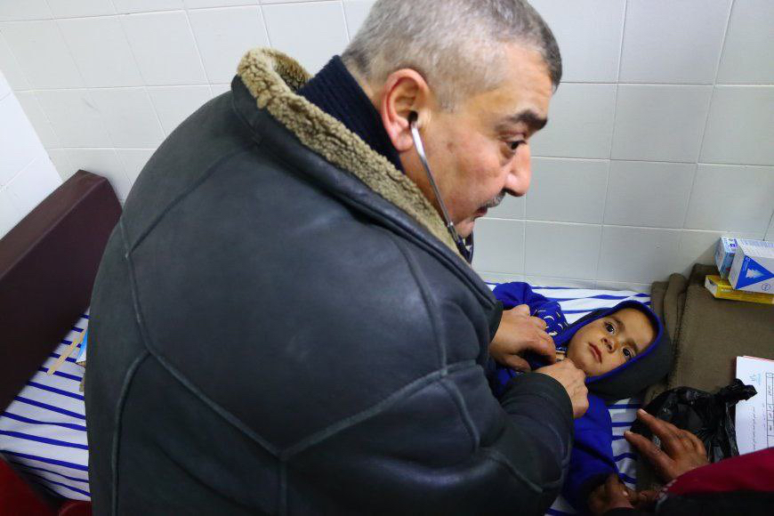 Врач осматривает ребенка в лагере беженцев в населенном пункте Табка