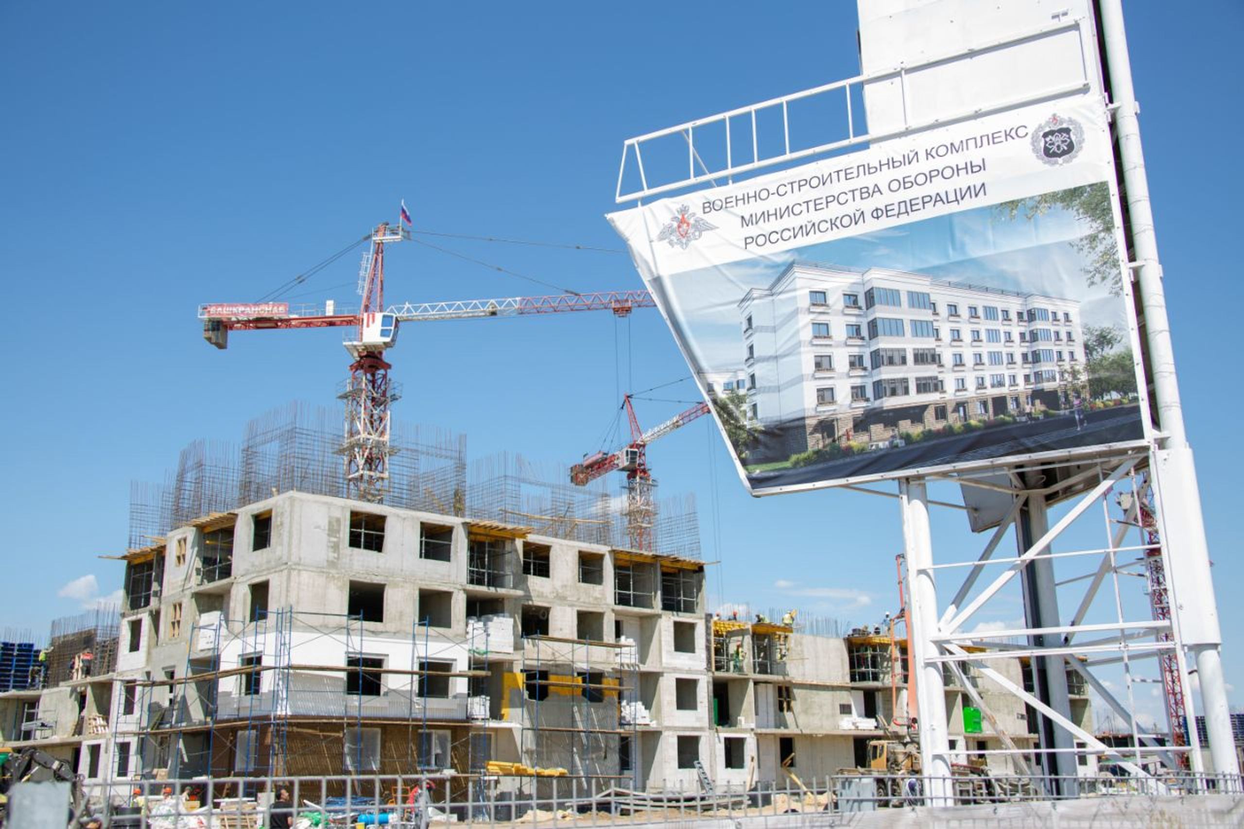 A building site in Mariupol. The image containing the render of the finished apartment block in the foreground reads “Military-Construction Complex of the Ministry of Defense of the Russian Federation”